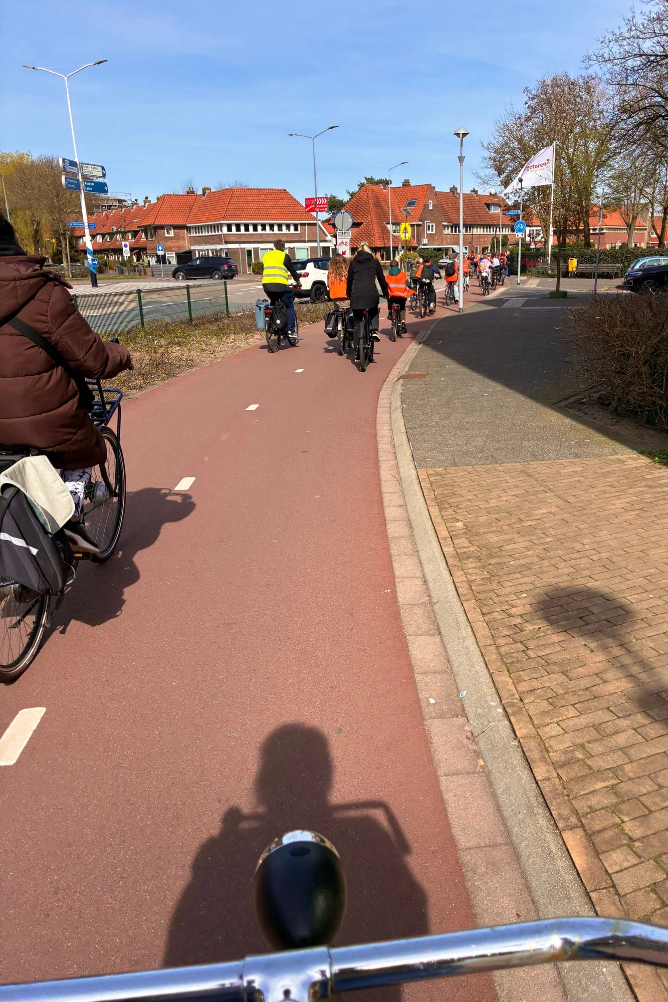 2026-03-20 - i16 - color - NL - Bike path with kids with orange jackets on