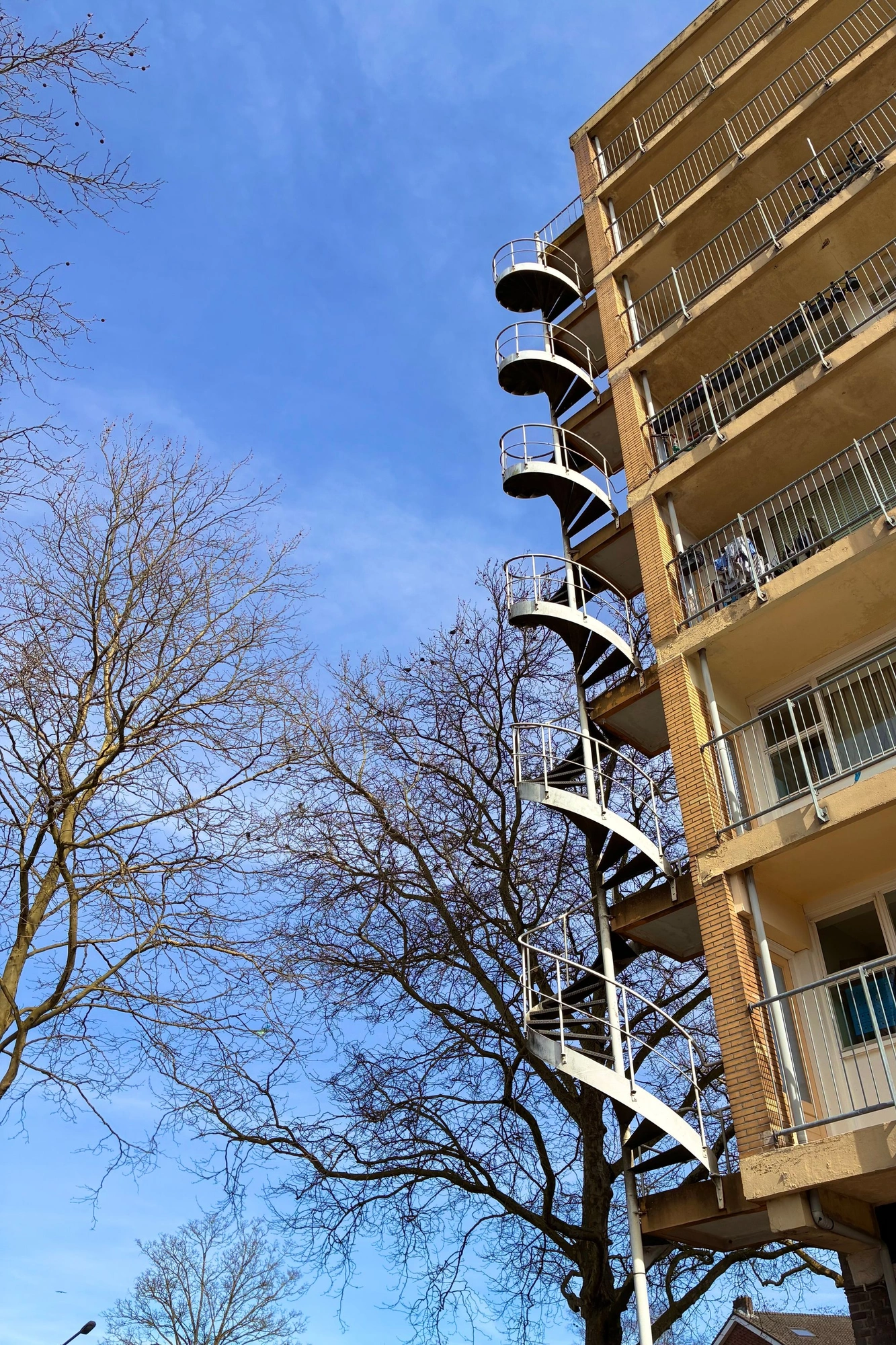 2026-03-20 - i16 - color - NL - Spiral staircase on side of appartment building