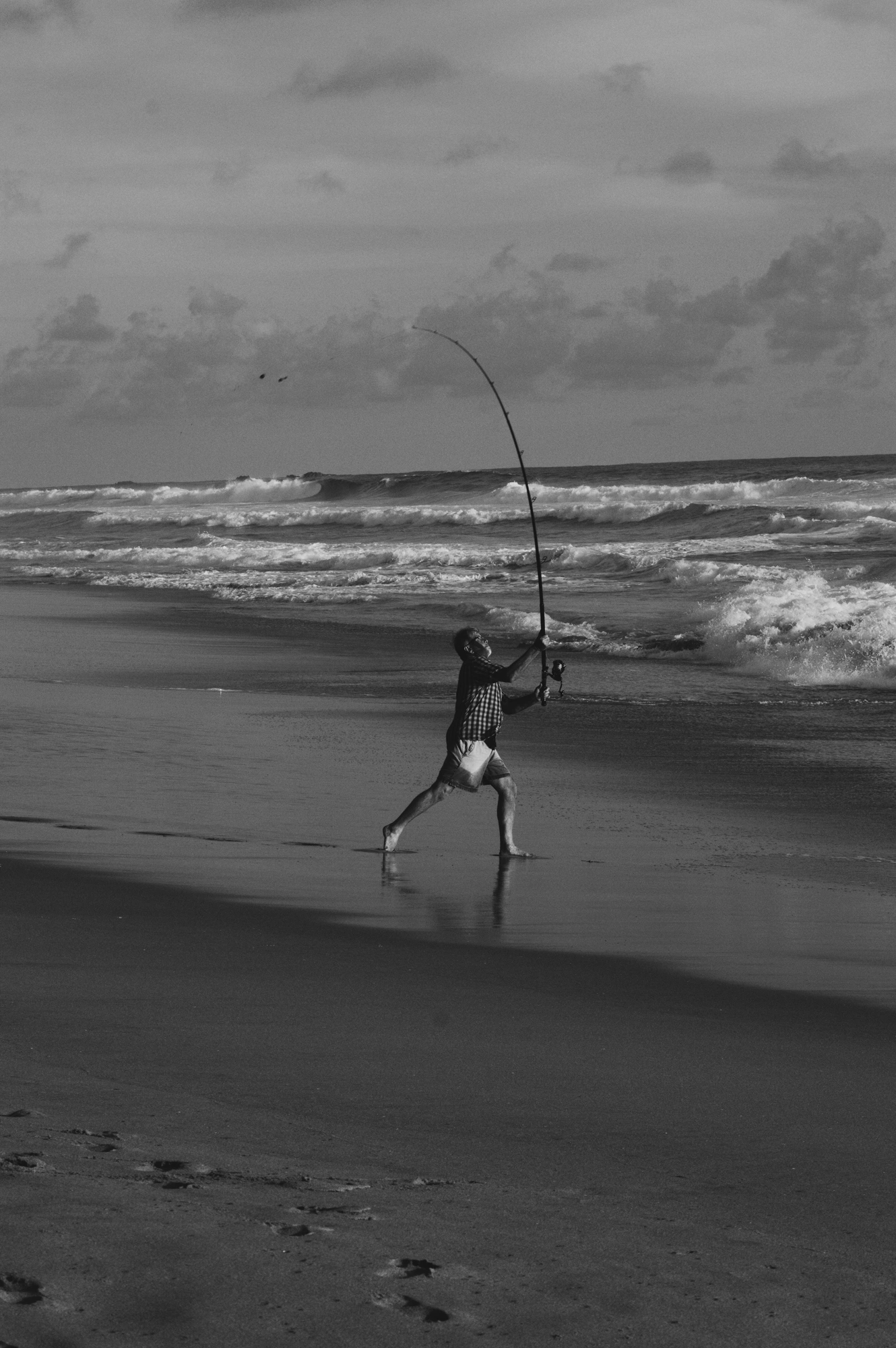 2018-12-24 - n18-55 - bw - ZA - Knysna - Fisherman casting a line from the beack
