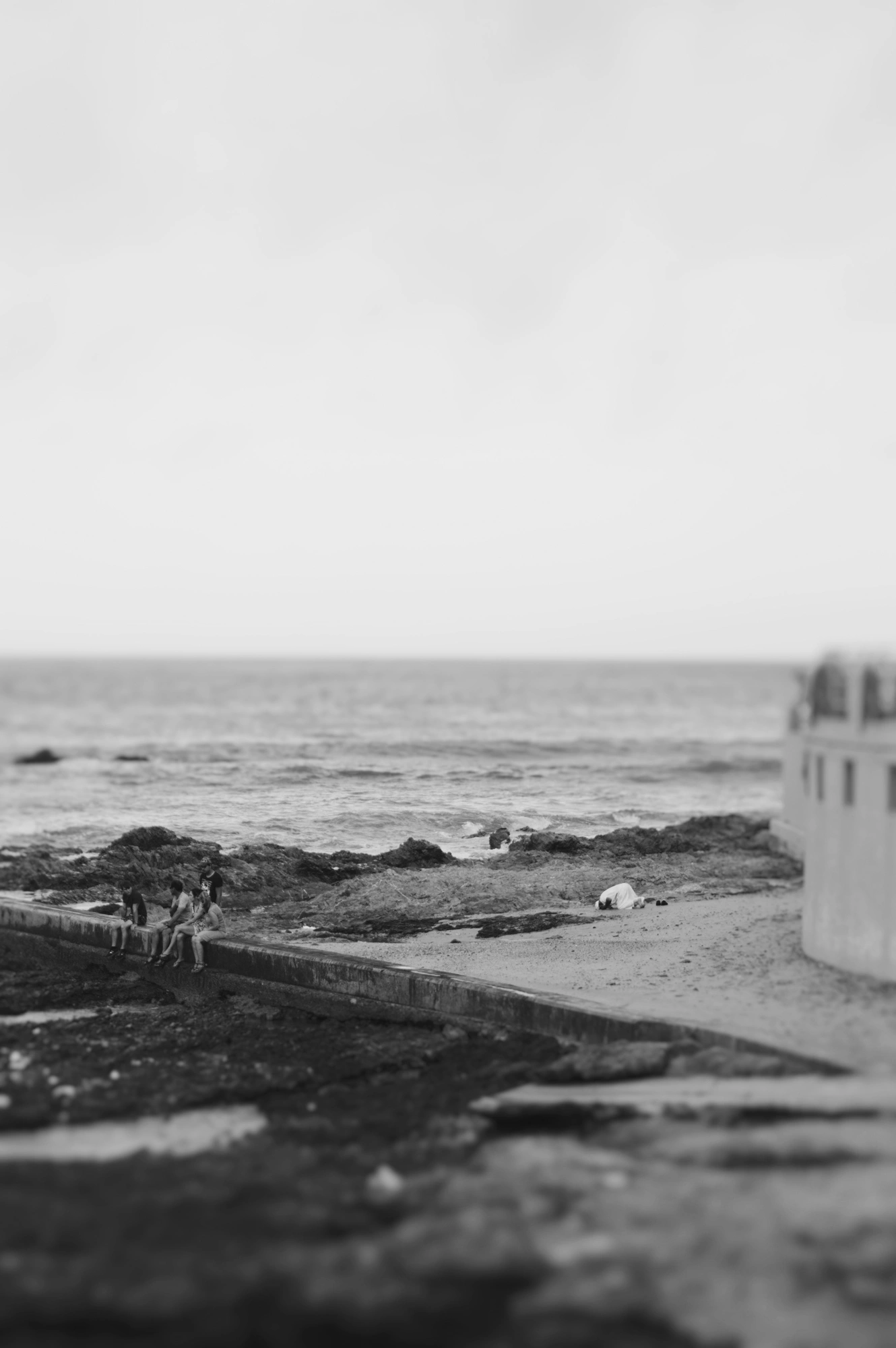 2018-22-12 - n18-55 - bw - ZA - Port Elizabeth - Man prays in distance with people sitting to the left next to the ocean