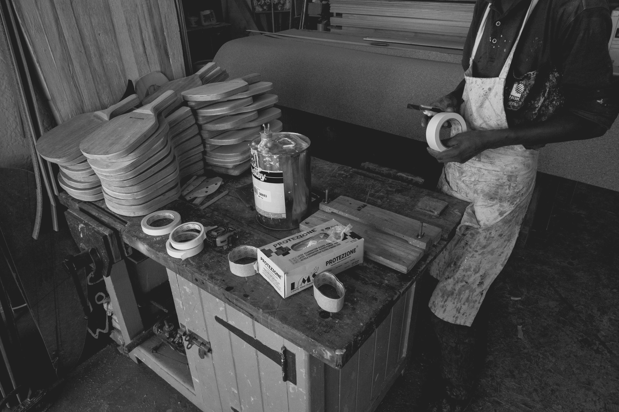 2022-02-14 - xt15-45 - bw - ZA - Cape Town - Man cuts masking take while constructing surfboard