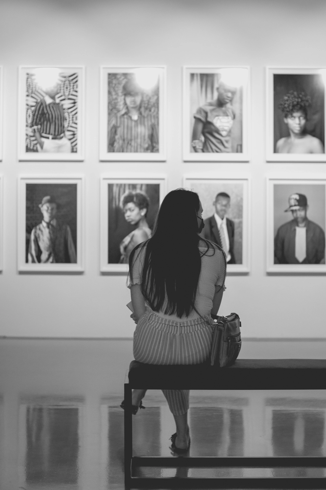 2022-02-16 - xt35 - bw - ZA - Cape Town - Person sits on bench looking at photos on the wall