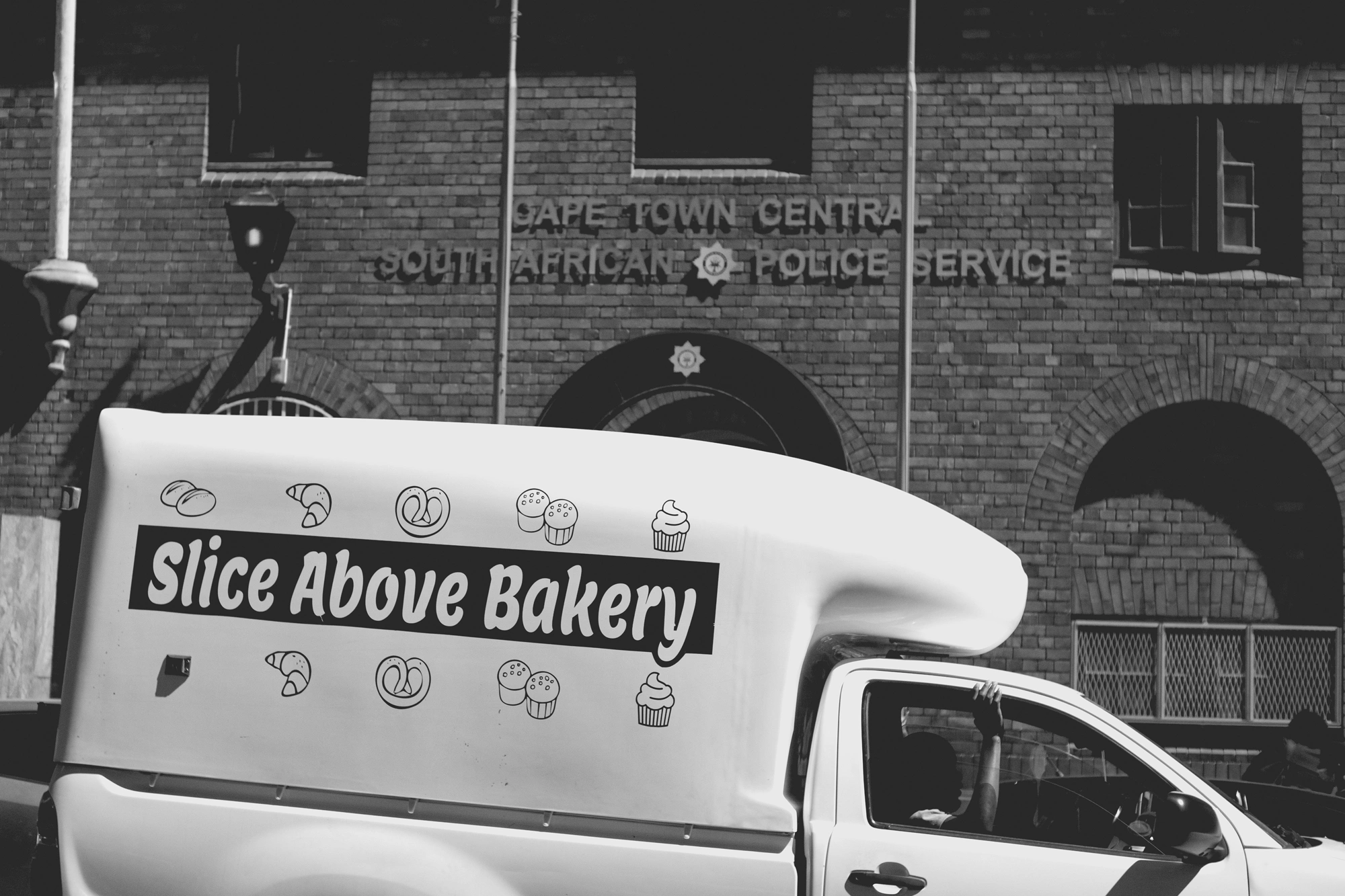 2022-02-17 - xt35 - bw - ZA - Cape Town - Man with arm out of window in a delivery van in front of a police building