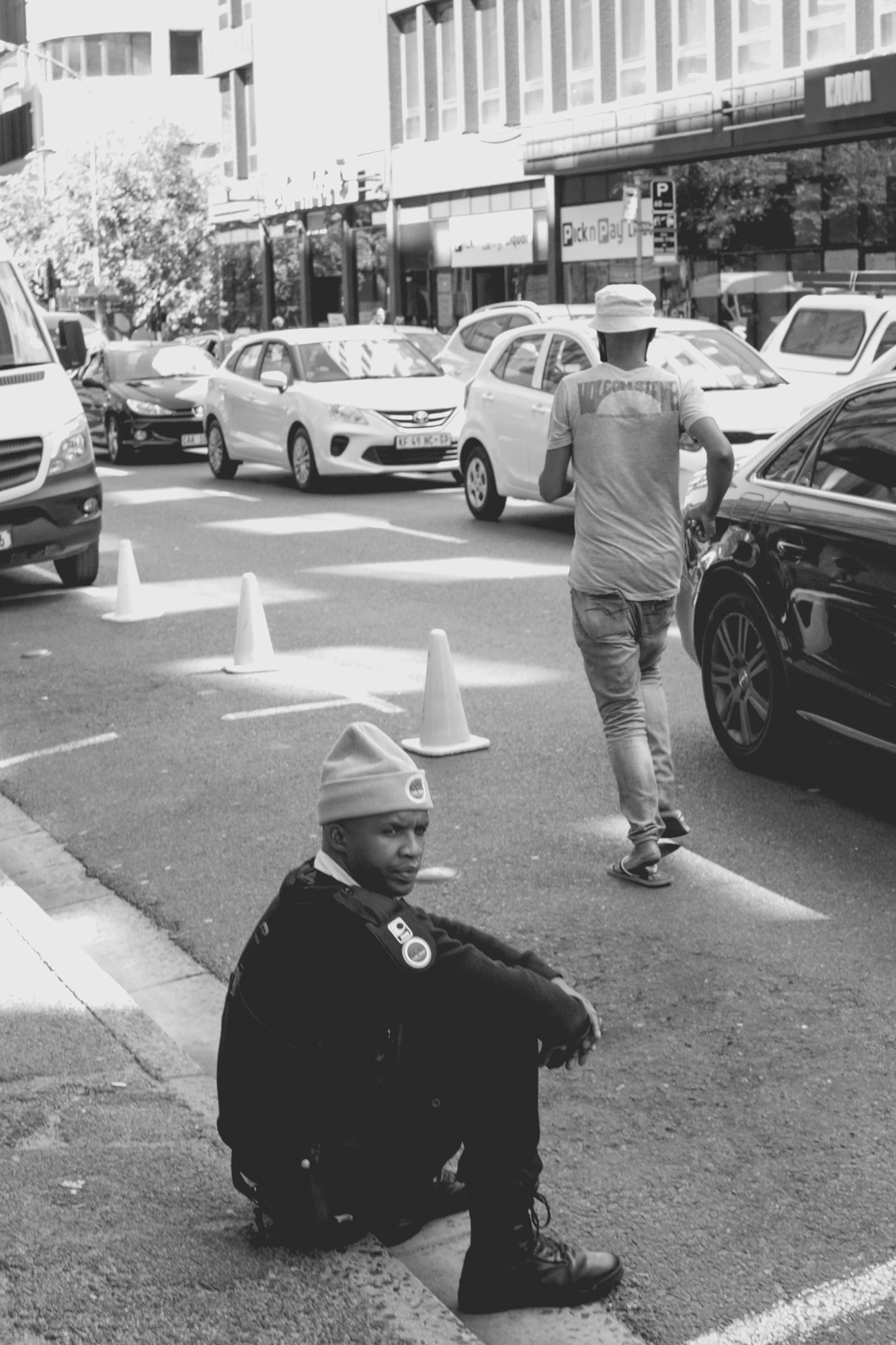 2022-02-17 - xt35 - bw - ZA - Cape Town - Security guard sitting beside the road