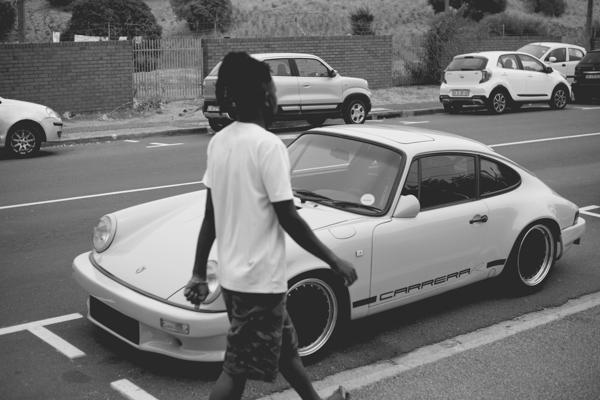 2022-02-18 - xt35 - bw - ZA - Cape Town - Man walking beside porsche