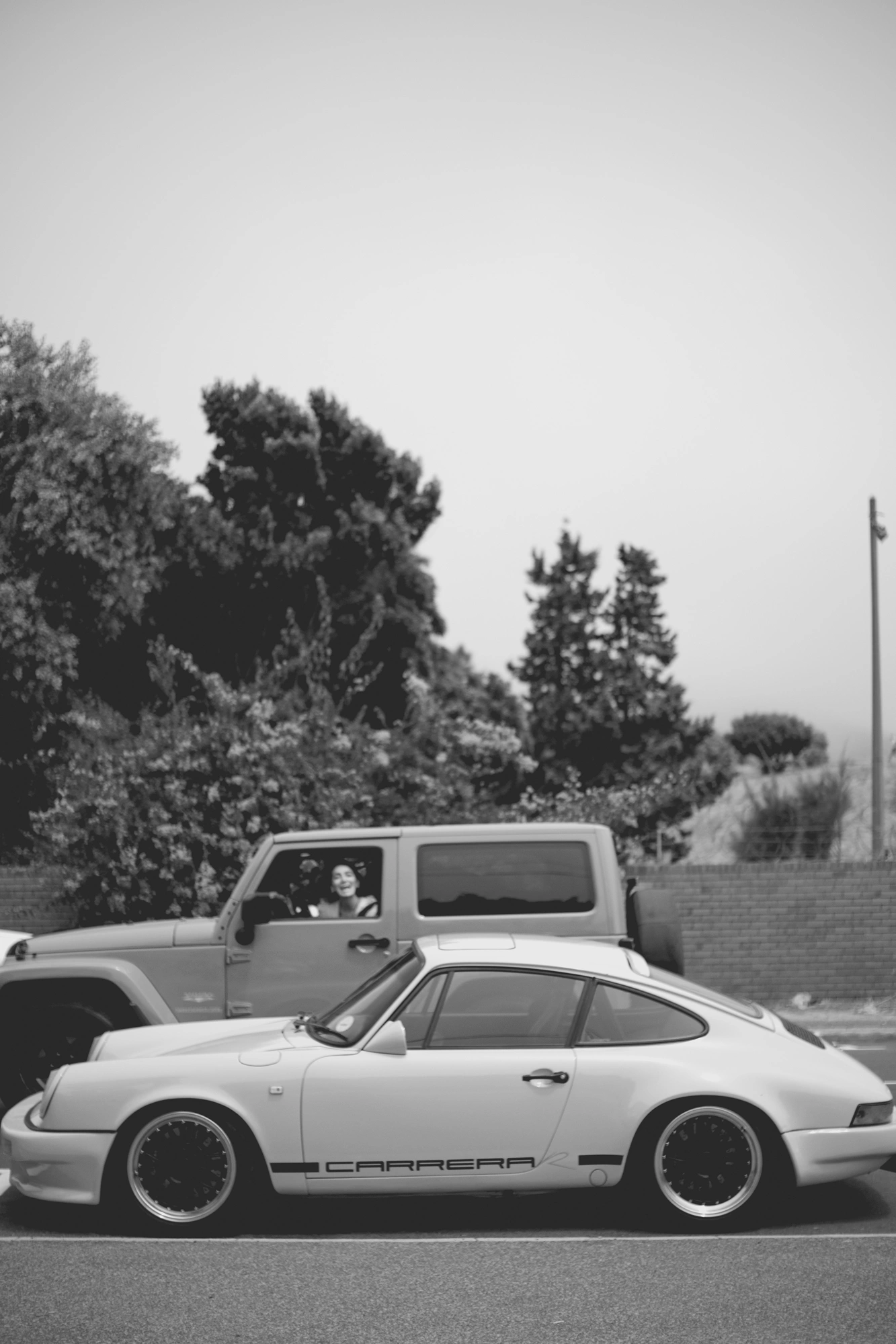 2022-02-18 - xt35 - bw - ZA - Cape Town - Porsche parked with person driving in a jeep shouting out of window