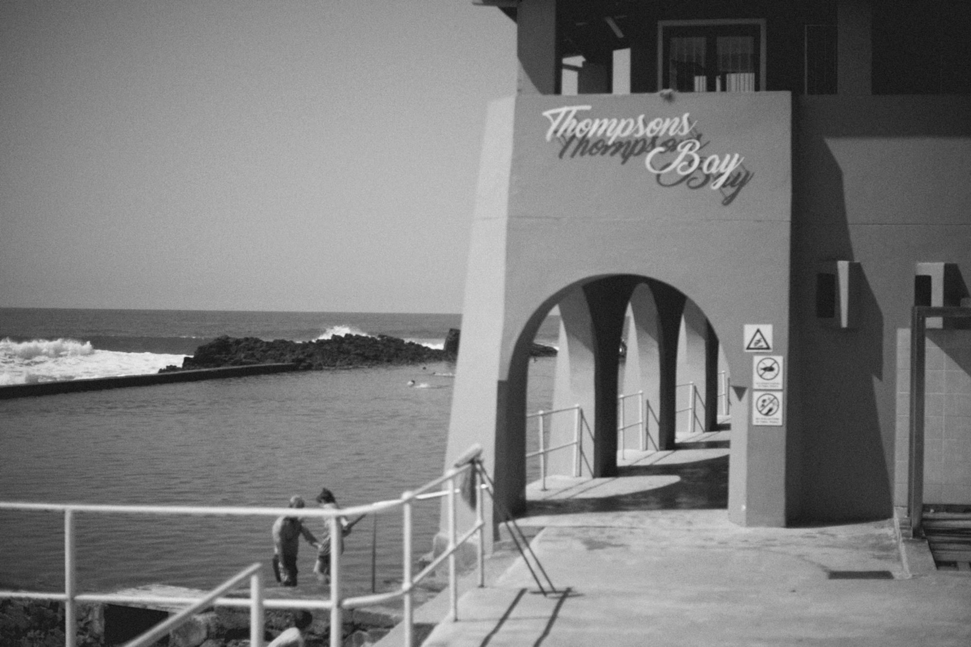 2022-09-22 - xt35 - bw - ZA - Durban - Pathway alongside a tidal pool with sign that reads 'Thompsons Pier'