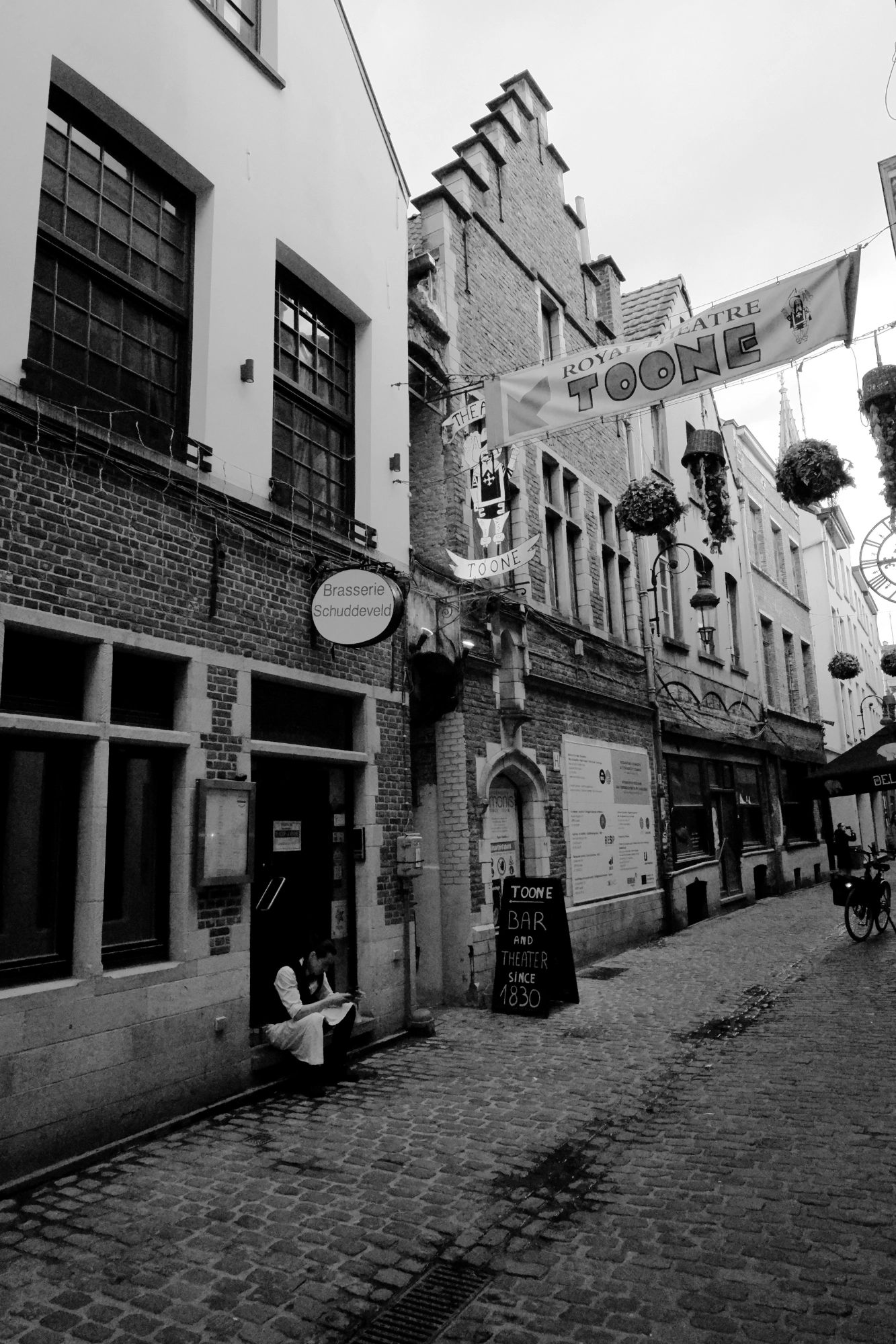 2024-06-16 - xt35 - bw - BE - Brussles - Street with person sitting outside of building