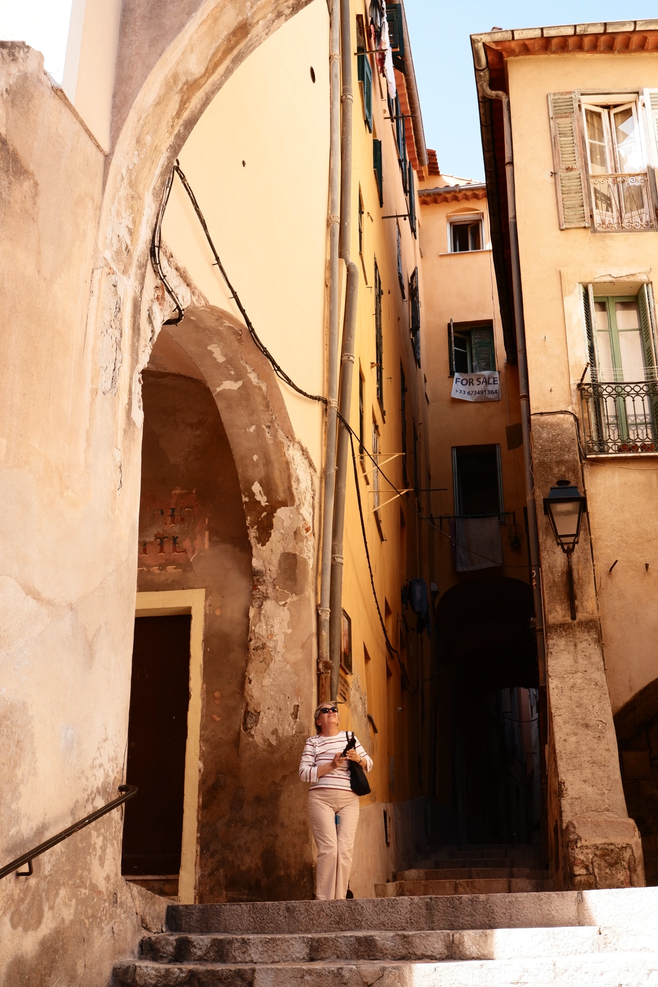 2025-09-08 - xt15-45 - color - FR - Menton - Person standing amongst small orange buildings