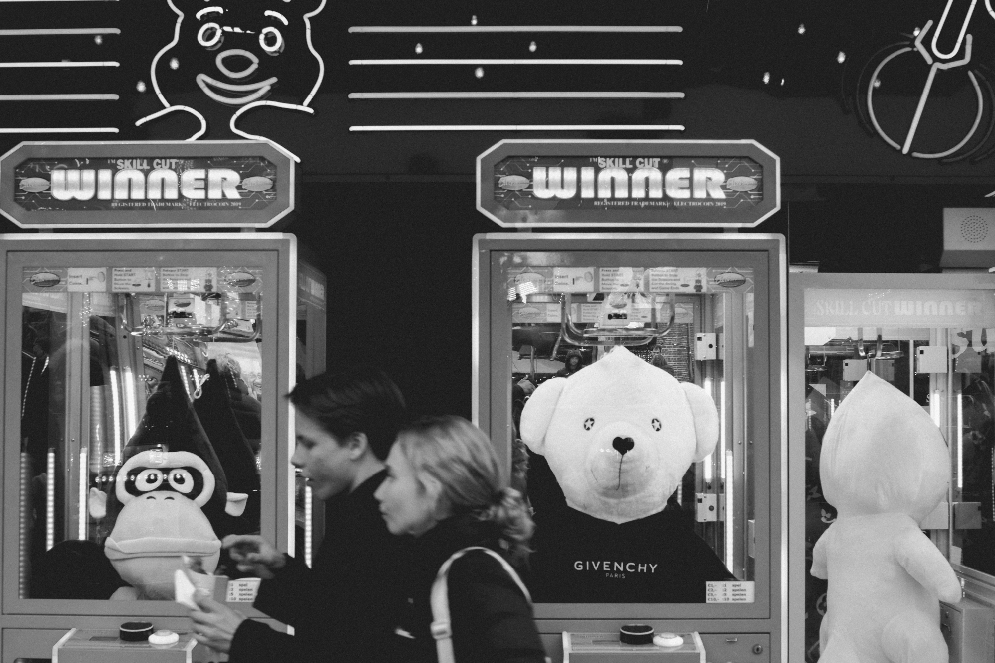 2024-04-18 - xt35 - bw - NL - Person walking past claw machines