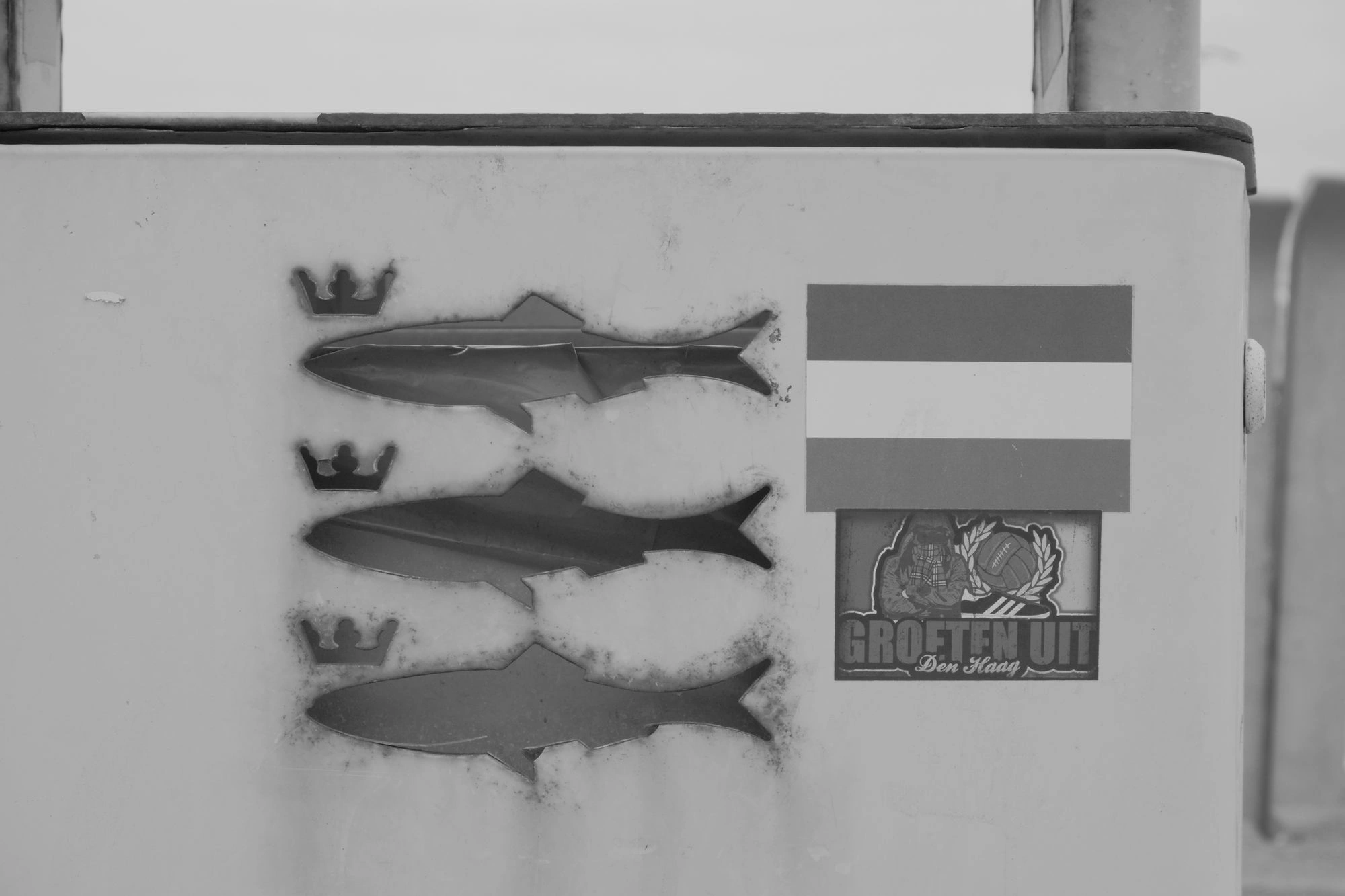 2026-07-18 - Scheveningen - Three fish with crowns next to a dutch flag on the side of a bin.J