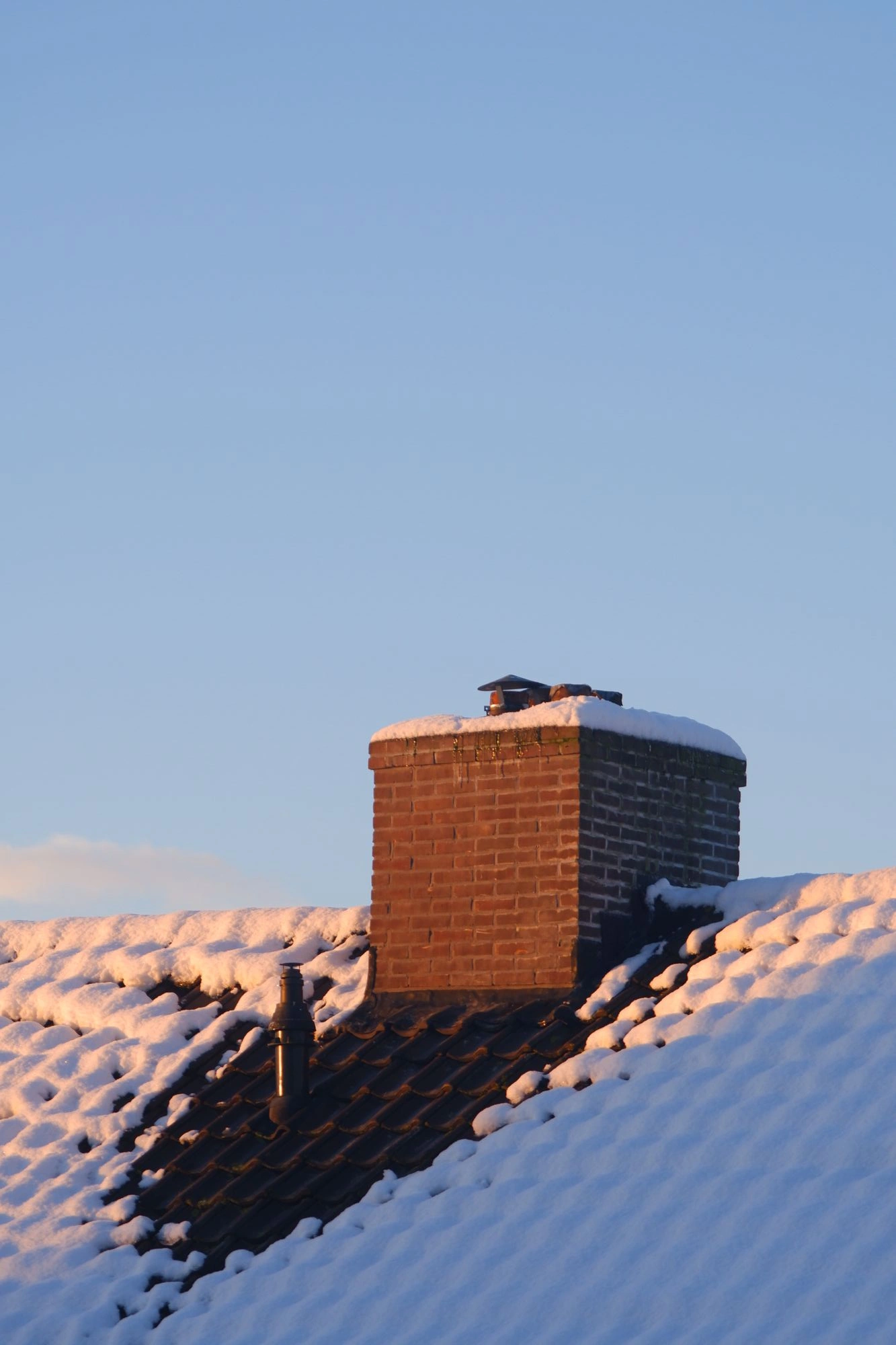 Snow on roof with sun hitting the chimney.J