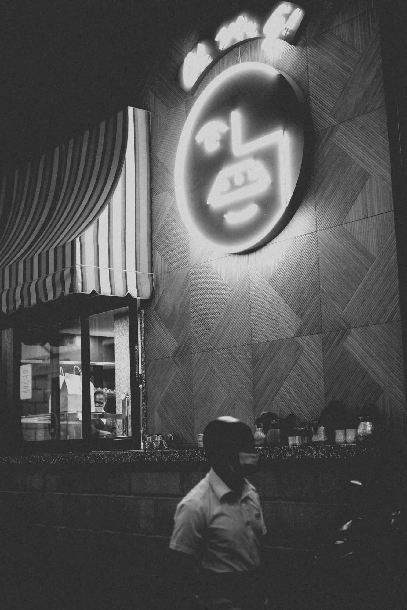 2021-12-04 - Melrose Arch, Johannesburg -  Waiter walking in front of restuarant sign.j